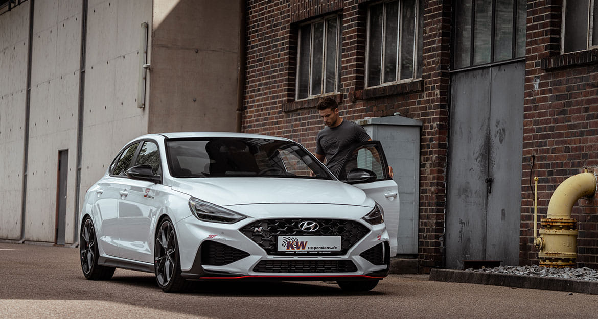 Junger Mann steigt in einen weissen Hyundai i30 N mit KW V3 Gewindefahrwerk ein